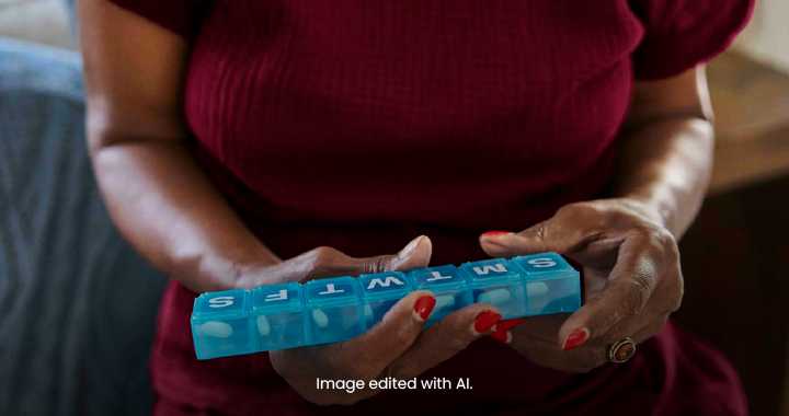Photograph showing a person holding a blue weekly pill organizer labeled with days of the week from Sunday to Saturday.