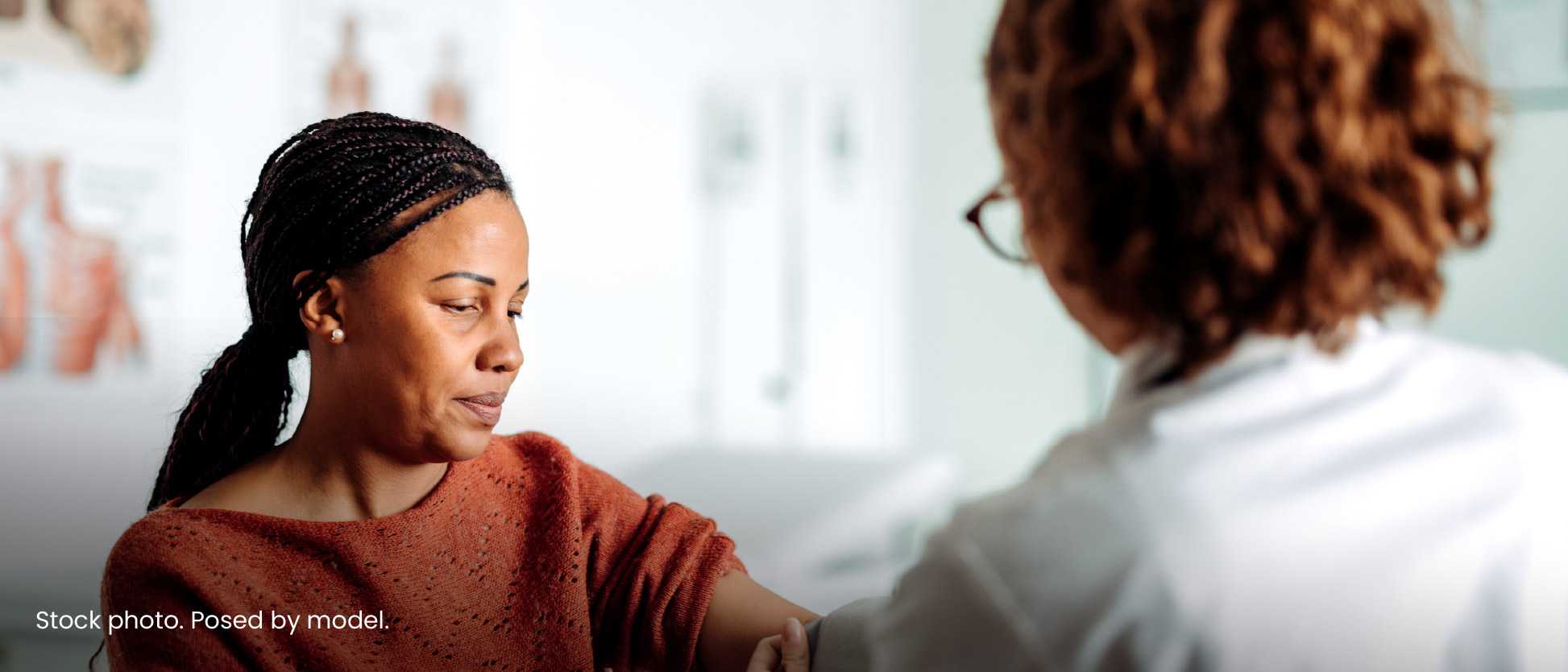 Photograph showing a healthcare professional administering a vaccine to a woman wearing a rust-colored sweater. The setting appears clinical with bright lighting, and a small HIV.gov logo is visible in the bottom right corner, indicating a focus on HIV-related healthcare or vaccination.
